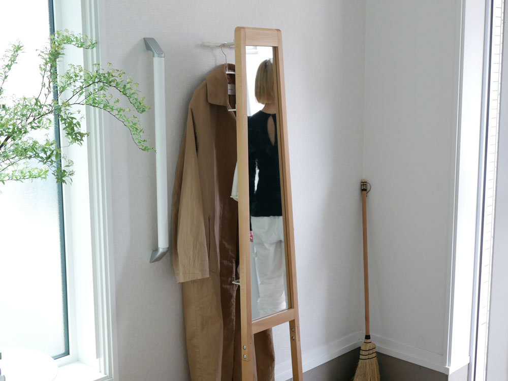 天然木フレームの「リヴ 立て掛けミラー」が木製フローリングの上に清潔感を持って配置されているインテリアの様子