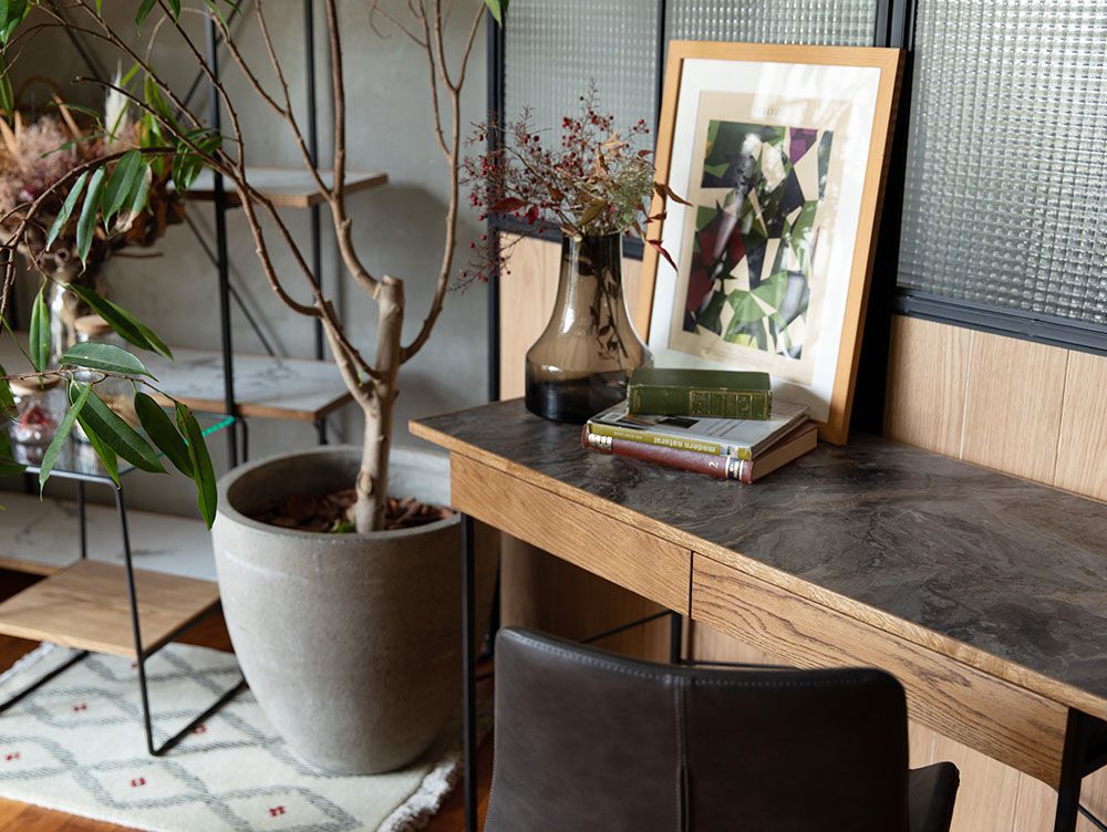 オーク無垢材とスチールフレームで作られたPOLデスクが、木製床と花鉢とともに洗練された室内に配置されています。