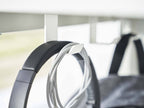 タワー製デスク下用3連フックがスチール製でシルバー色、デスク下に取り付けられ、電気ケーブルや衣類ハンガーを掛けている様子