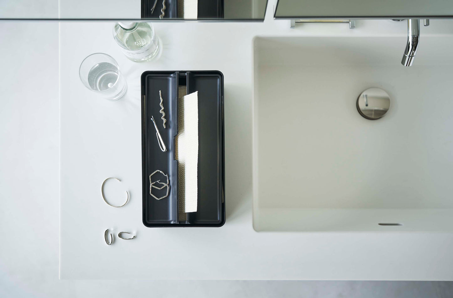 銀色のバスルームシンクと蛇口の隣に設置された「タワー」トレー蓋付きペーパータオルケース。