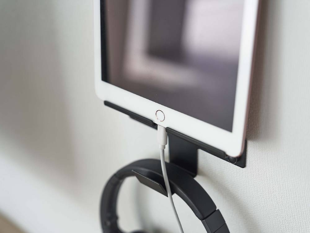 【smart/スマート】ウォール スマートフォン&ヘッドホンホルダーが壁に取り付けられ、スマートフォンとヘッドホンを整理して収納している様子