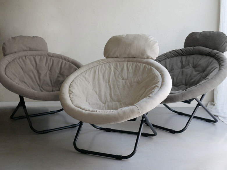 リビングルームの床に置かれたグレーのアームレスト付き2wayフォールディングチェア、自然素材を使用した快適なデザイン。