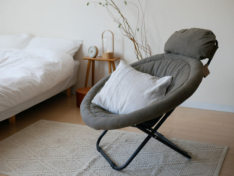 グレーの木製2wayフォールディングキャンバスチェアが、木張りの床のある快適な室内に配置されています。