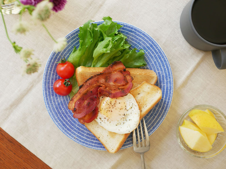 アラビア24hアベックプレートに盛られたパン、目玉焼き、肉などの朝食料理