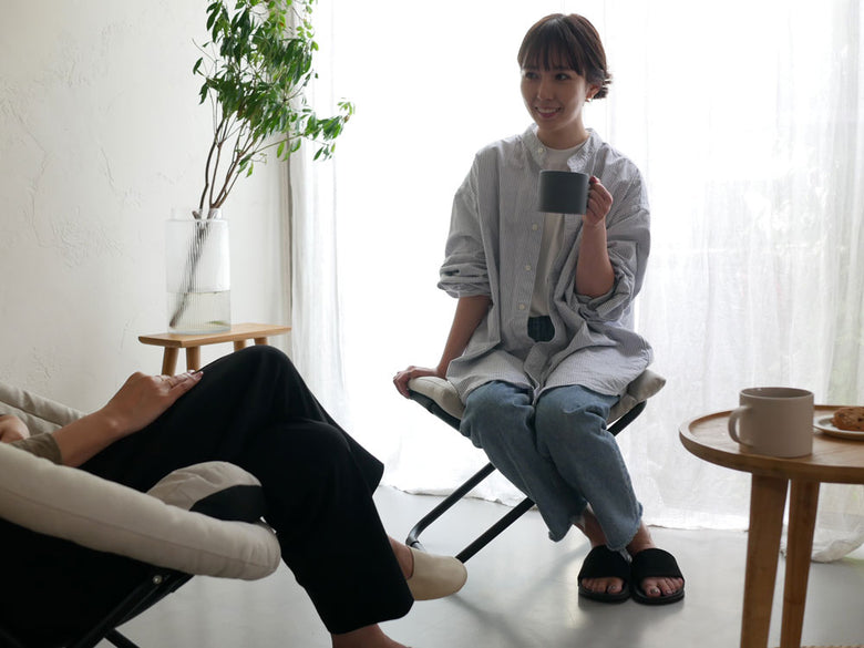 【Comore Sun】2wayフォールディングチェアとオットマンを使用して快適に座り、アームレストに手を置きながら足をリラックスさせている様子