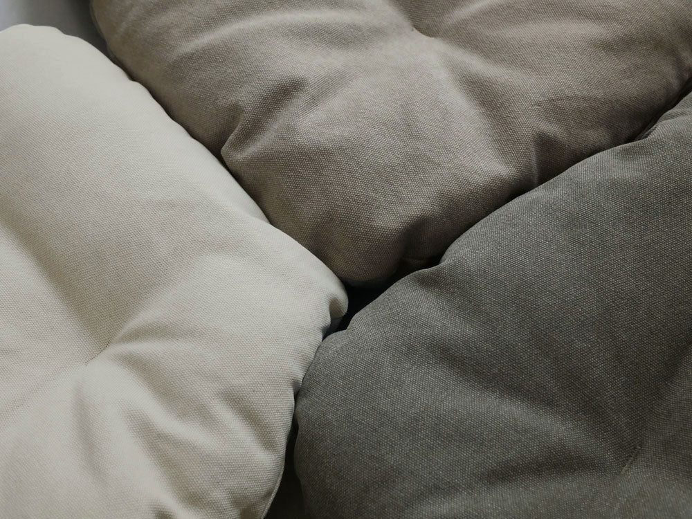 リビングルームに配置された【Comore Sun】2wayフォールディングチェア用キャンバスクッションと、クッションやデイベッド、食事のアイテムが整えられた快適な空間