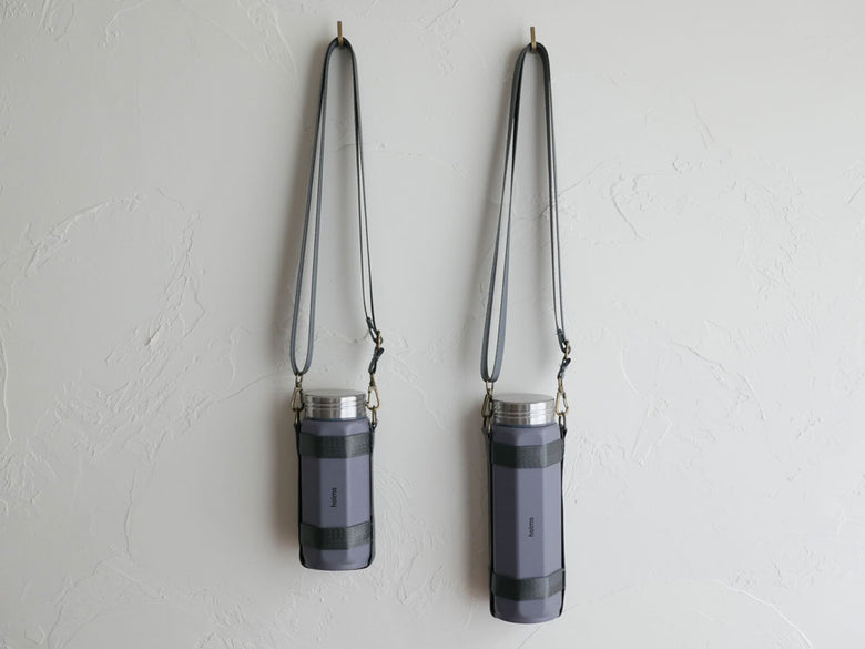 CB JAPANのholmsオクタボトル ロングショルダー、銀色のアルミニウムとプラスチック製シリンダー型水筒に長めのショルダーホルダー付き
