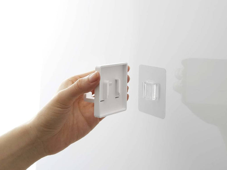 MISTフィルムフックシェーバーホルダーのプラスチック製ホルダーが壁に取り付けられている様子。ABS樹脂で作られ、複数のフィルムフックが配置されています。