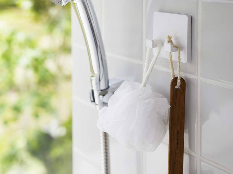 浴室の壁に取り付けられた【MIST/ミスト】フィルムフックシェーバーホルダーにタオルやブラシが掛かっている様子