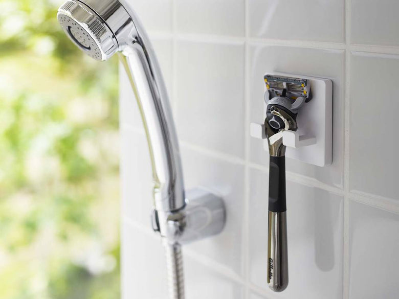 ミストのシェーバーホルダーが光沢のある壁面にフィルムフックで取り付けられており、複数のフックにシェーバーが掛かっている様子