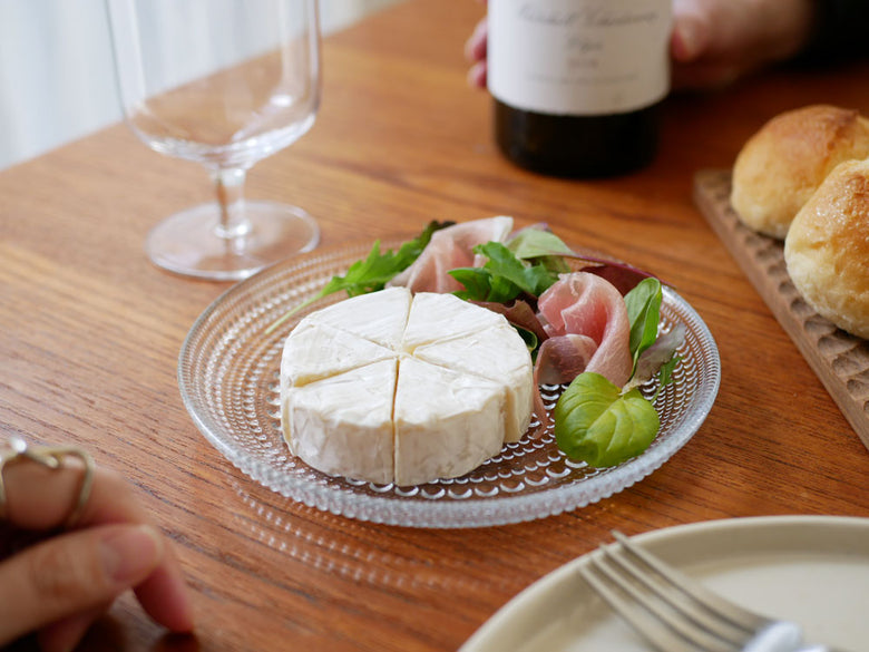 イッタラ製カステヘルミ無鉛ガラスプレートにチーズ、パン、フルーツが盛り付けられた食卓の画像