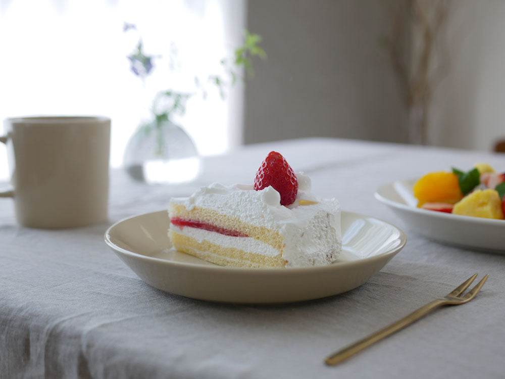 白いイッタラティーマ磁器プレートにケーキやフルーツが盛り付けられたテーブルウェアの配置