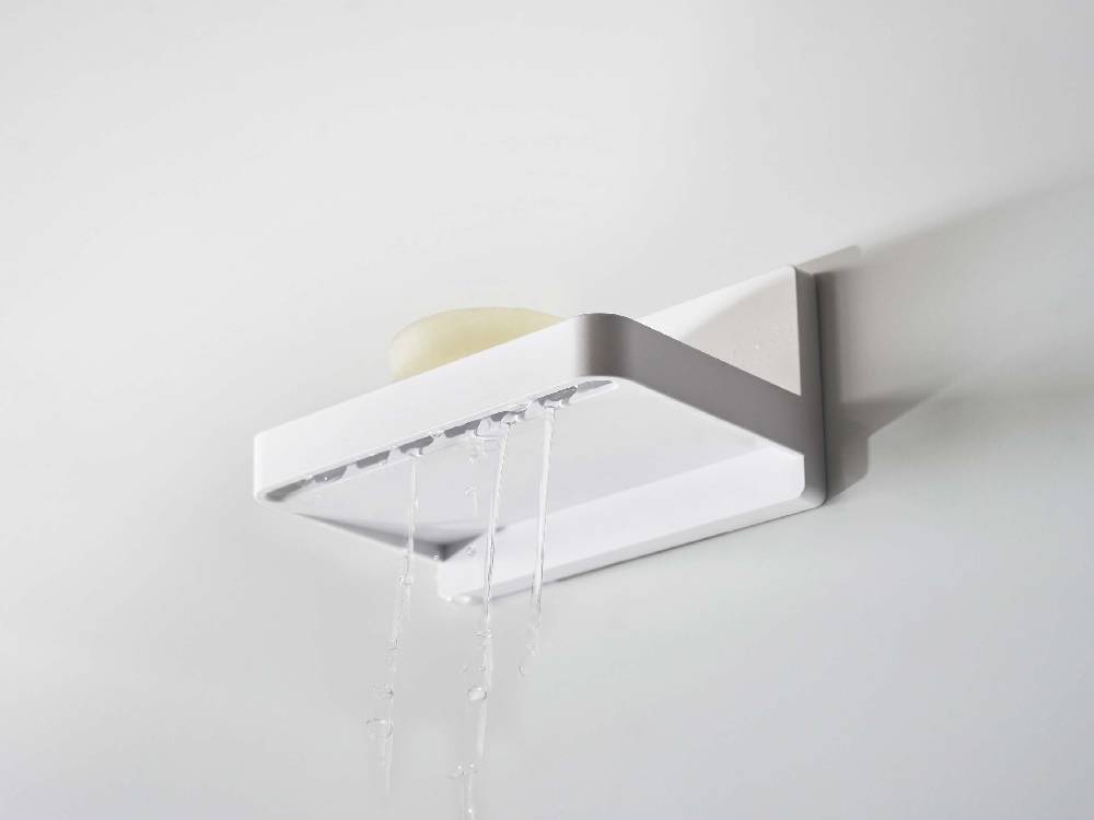 ABS樹脂製の「MIST/ミスト」フィルムフックソープトレーが光沢のある壁面に取り付けられており、水が流れるデザインが特徴的です。付属のフィルムフックが二つ使用されています。