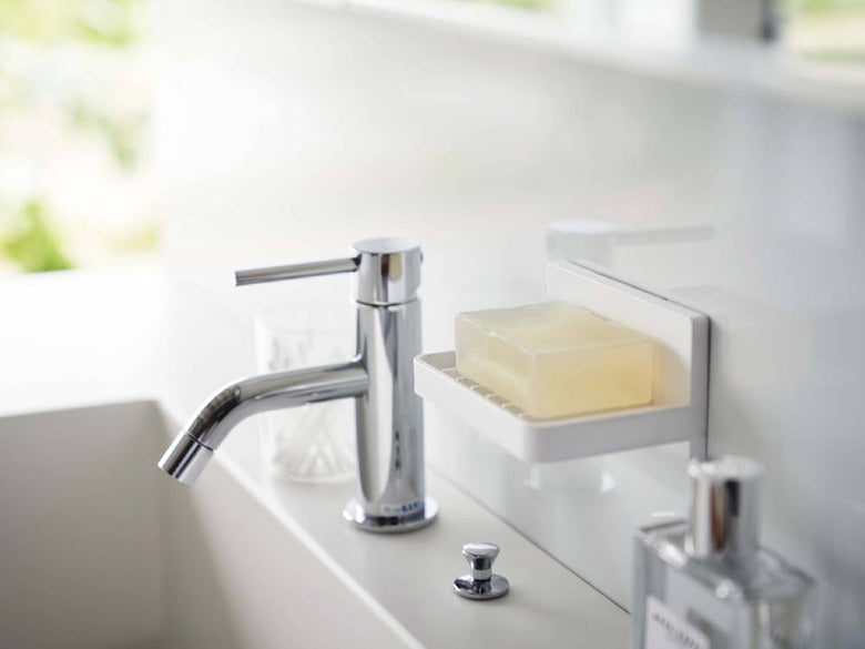 バスルームの洗面台にフィルムフックで取り付けられた「MIST/ミスト」水が流れるソープトレー。ABS樹脂製で実用的なデザイン