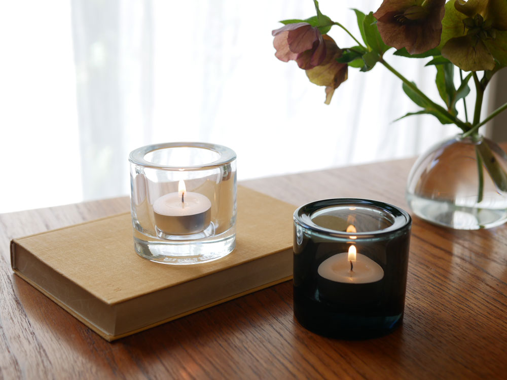 フィンランド製無鉛ガラスの【iittala/イッタラ】キビ キャンドルホルダーとキャンドルがテーブルに置かれている様子