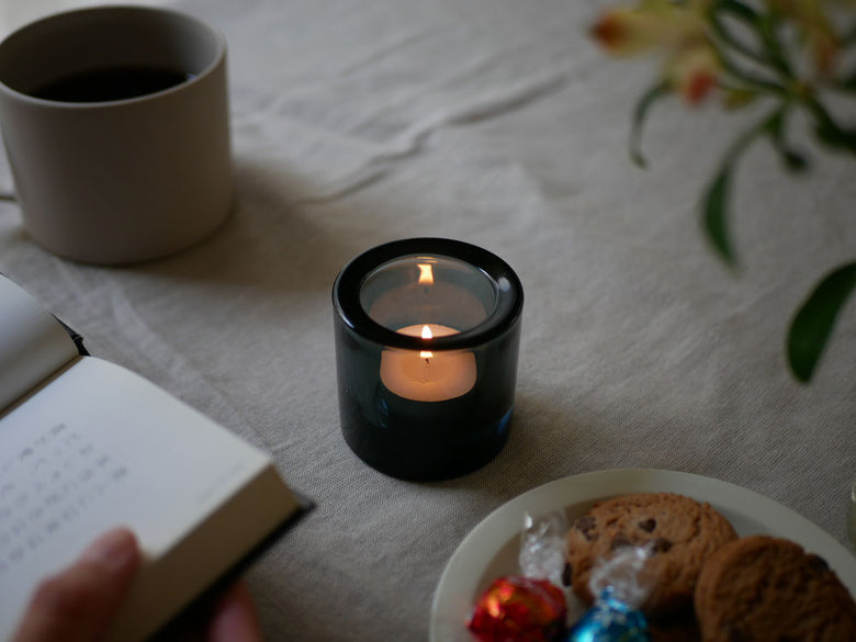 フィンランド製無鉛ガラスのイッタラ「キビ キャンドルホルダー」にろうそくの炎が灯され、テーブルウェアとともに配置された静物写真