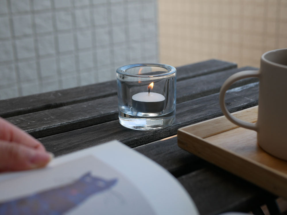 iittalaのフィンランド製無鉛ガラスキビ キャンドルホルダーに灯されたキャンドルとガラス食器が並ぶテーブル