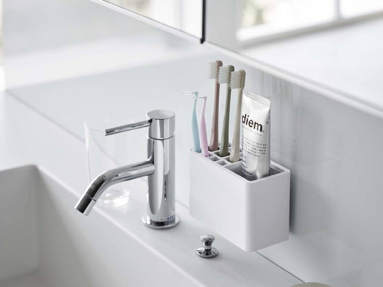 浴室の洗面台に取り付けられた[MIST/ミスト]フィルムフック歯ブラシスタンド。歯ブラシやソープディスペンサーを整理するプラスチック製のスタンド。