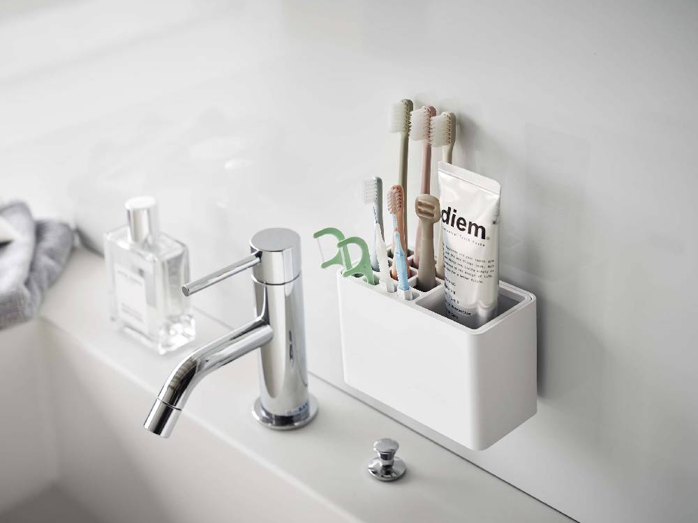 浴室のシンクに設置された【MIST/ミスト】フィルムフック歯ブラシスタンドと蛇口、ソープディスペンサー、観葉植物が見える様子