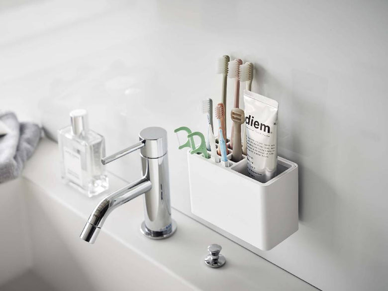 浴室のシンクに設置された【MIST/ミスト】フィルムフック歯ブラシスタンドと蛇口、ソープディスペンサー、観葉植物が見える様子