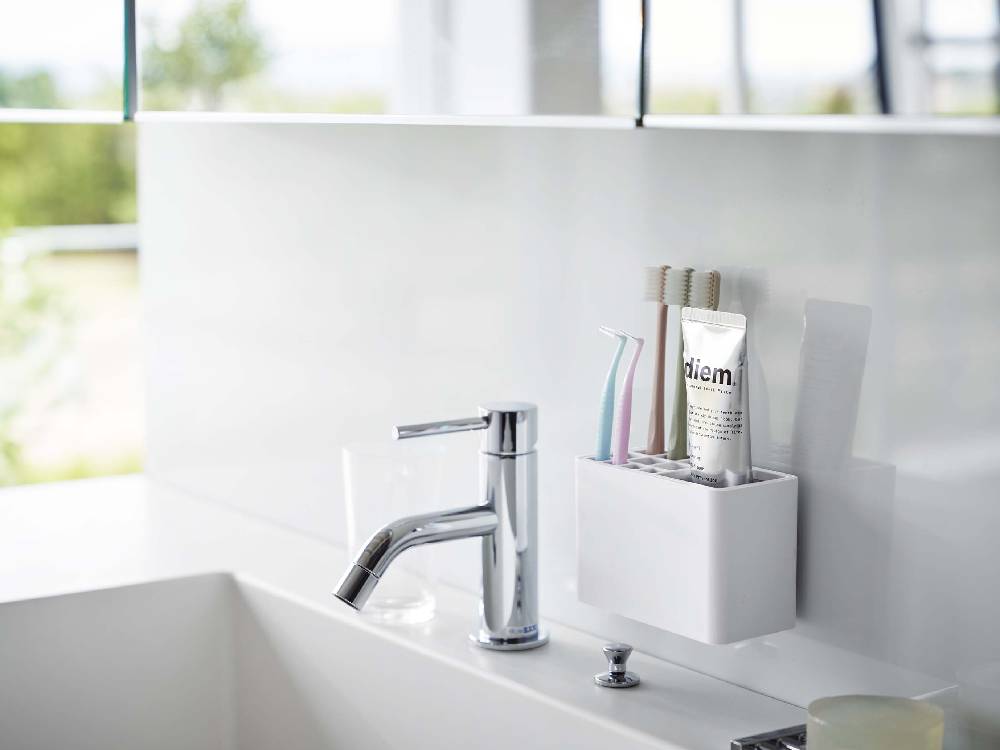 バスルームのシンクに設置された【MIST/ミスト】フィルムフック歯ブラシスタンドと蛇口、植物などの家庭用品