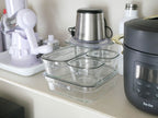 イワキのパック&レンジ システムセットの異なるサイズの耐熱ガラス容器とポリカーボネート製フタがキッチンのカウンタートップに並んでいる写真