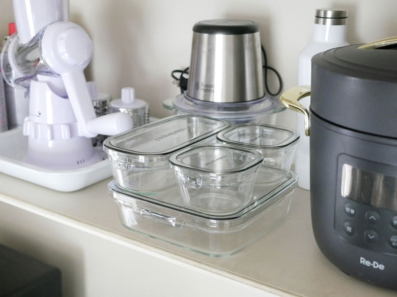 イワキのパック&レンジ システムセットの異なるサイズの耐熱ガラス容器とポリカーボネート製フタがキッチンのカウンタートップに並んでいる写真