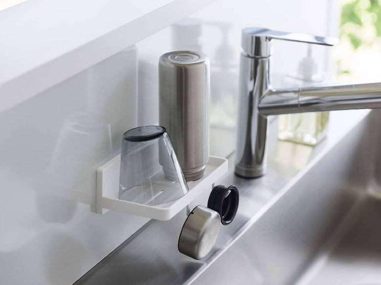 キッチンのシンクと蛇口、カウンタートップに置かれた家庭用ハードウェアと瓶