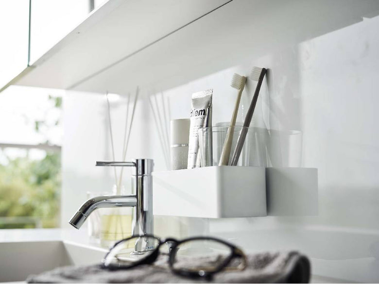 モダンなバスルーム内のシンクと蛇口が配置され、カウンターと棚が整然と整えられたインテリアデザイン