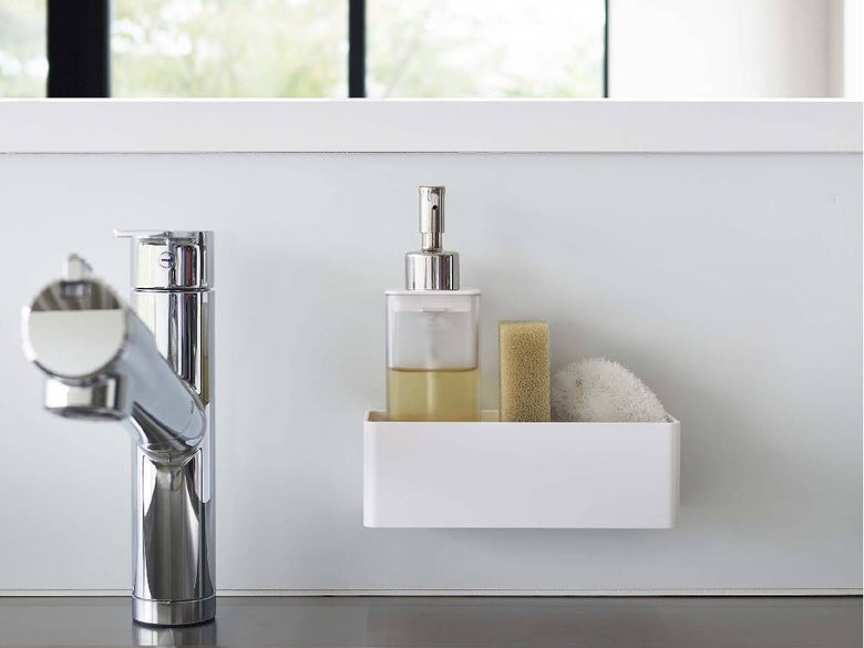 バスルームの洗面台に【MIST/ミスト】フィルムフックラック W18が設置され、蛇口やソープディスペンサー、ボトル、観葉植物が並んでいる様子