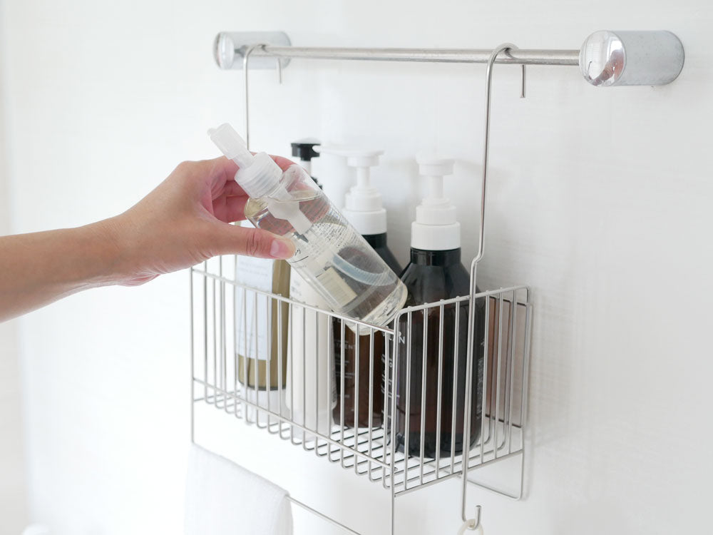 18-8ステンレス製の引っかけ式お風呂バスケットが浴室のタオルバーに掛けられ、ボトルや石鹸ディスペンサーなどのパーソナルケア用品が整理されている様子