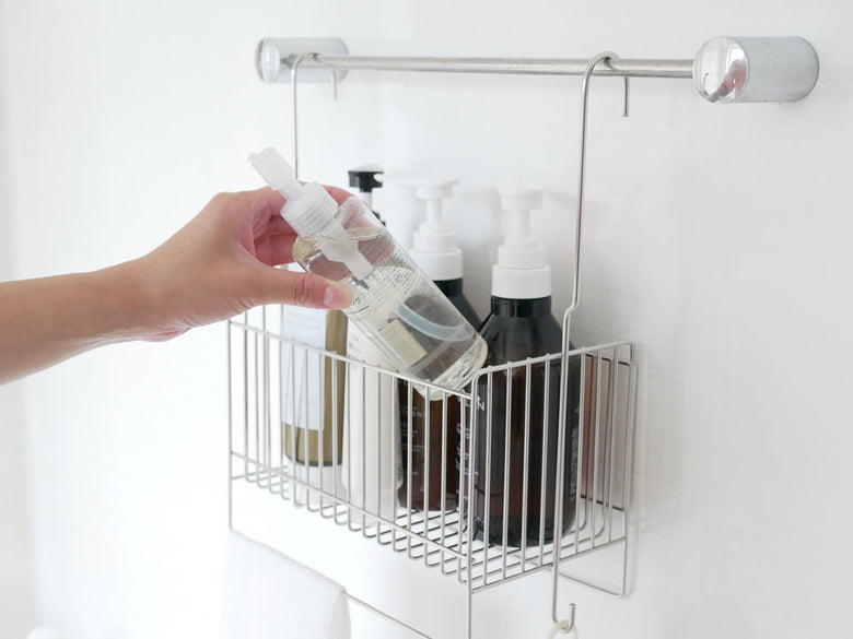 18-8ステンレス製の引っかけ式お風呂バスケットが浴室のタオルバーに掛けられ、ボトルや石鹸ディスペンサーなどのパーソナルケア用品が整理されている様子