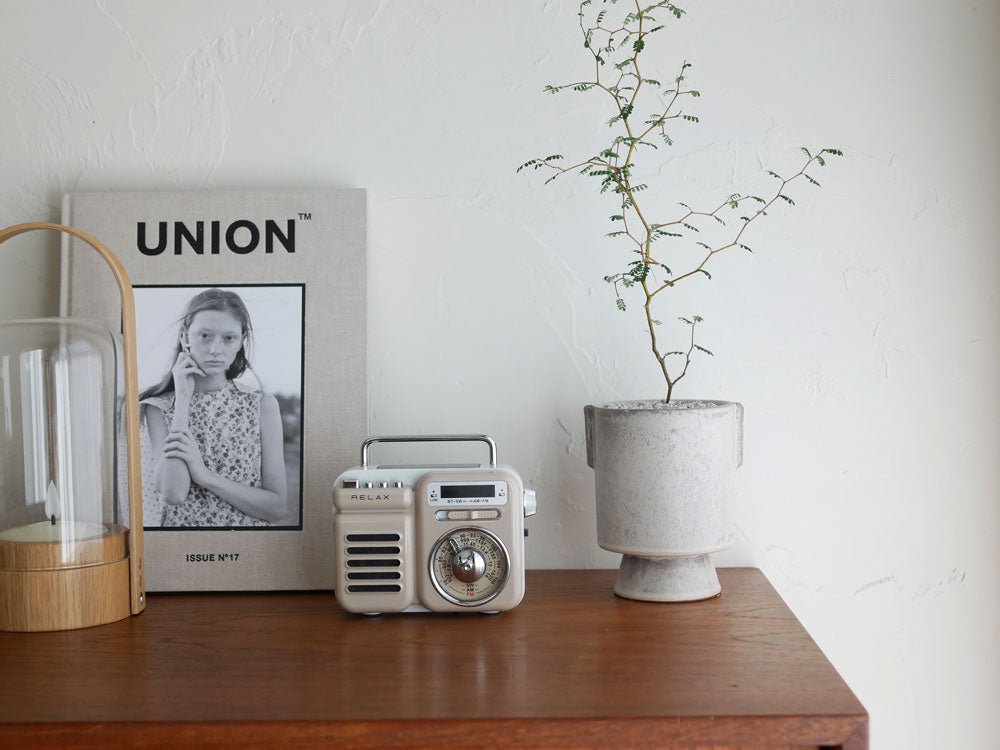 レトロかわいいデザインの多機能防災ラジオ「RELAX/リラックス」を家庭用電化製品や植物と共に配置した静物写真