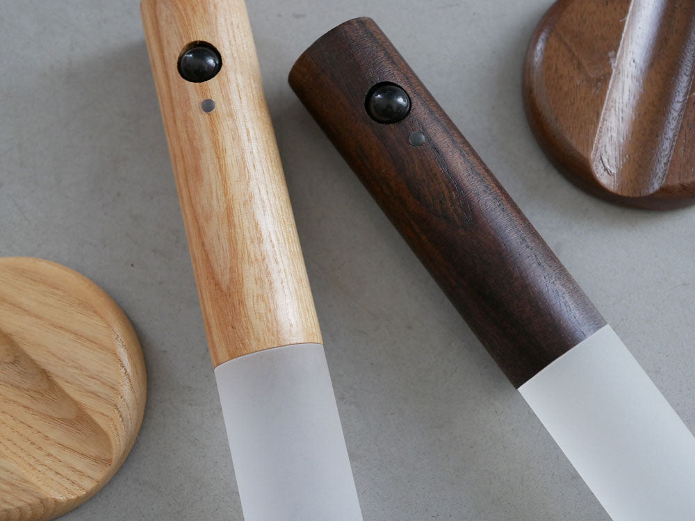 木製とアクリルで作られたオプト スティックセンサーライトがスタンドに取り付けられ、割り箸やペンなどの文房具とともに配置された写真