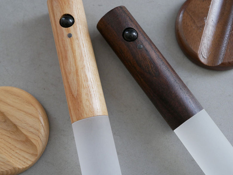 木製とアクリルで作られたオプト スティックセンサーライトがスタンドに取り付けられ、割り箸やペンなどの文房具とともに配置された写真