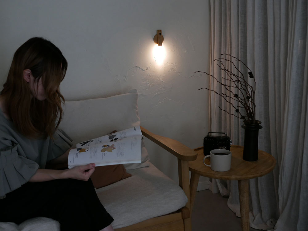 オプトのスティックセンサーライトがリビングルームのテーブルに置かれ、木とアクリル素材でデザインされた温かいLED光を提供する照明器具