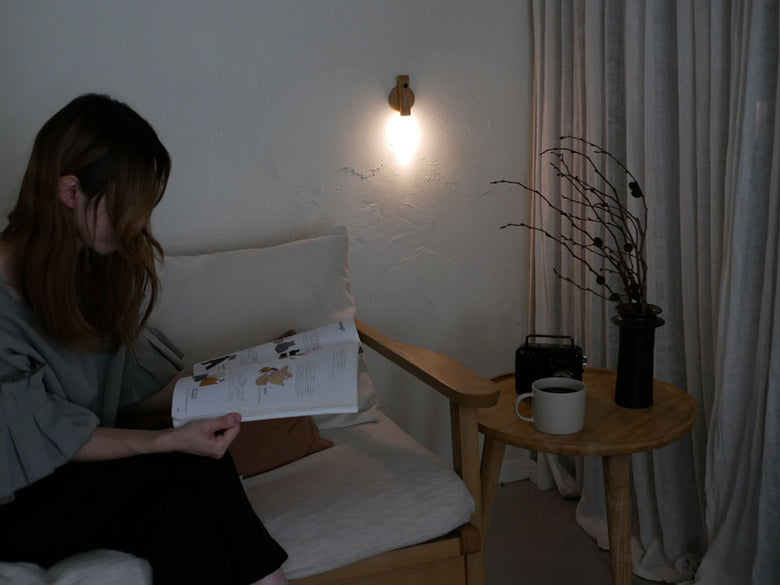 オプトのスティックセンサーライトがリビングルームのテーブルに置かれ、木とアクリル素材でデザインされた温かいLED光を提供する照明器具