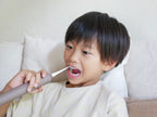 子供がエペイオス音波電動歯ブラシを使って笑顔で歯を磨いている様子