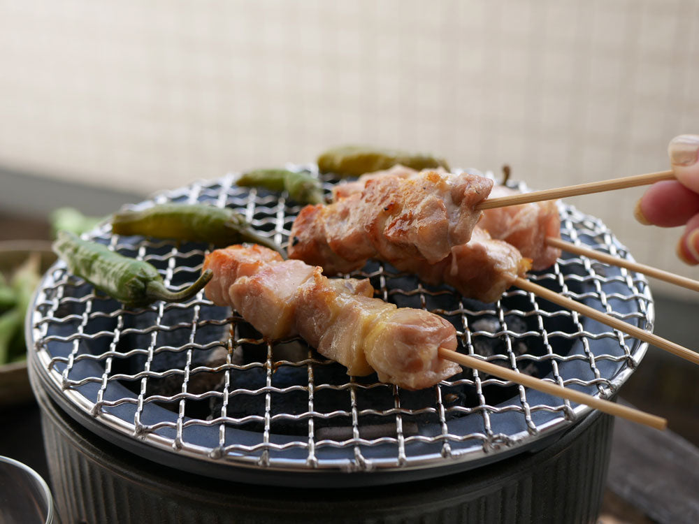 美濃焼の炭焼き水コンロを使用して屋外で肉をグリルしている様子