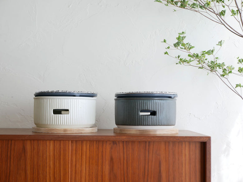 サリューの美濃焼炭焼き水コンロセット。陶器製本体、耐熱インナー、天然木のなべしき丸、トング、焼網が並んでいる