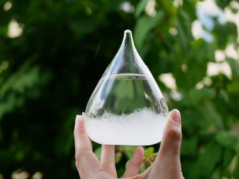 透明なガラス製容器に水とエタノールが混ざった液体が入っており、滴や泡が浮かび光を反射している様子