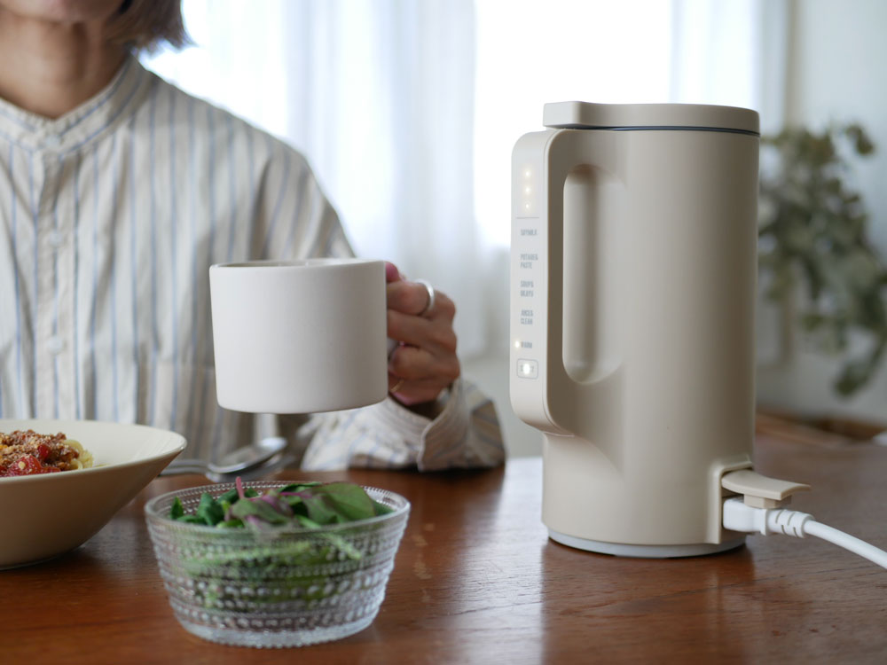 クリームホワイトの【recolte】自動調理ポット本体とフタ、計量スプーン、お手入れブラシが並んだ家庭用キッチン家電