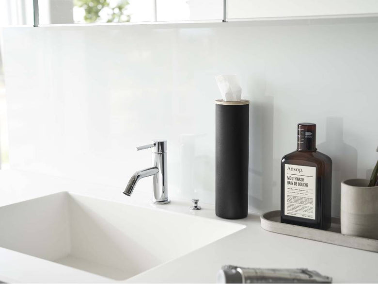 バスルームの洗面台に設置された【RIN/リン】ボトル型ティッシュケース S。スチールと天然木の素材がセラミック製の洗面ボウルや水栓金具と調和し、インテリアデザインの一部として配置されています。