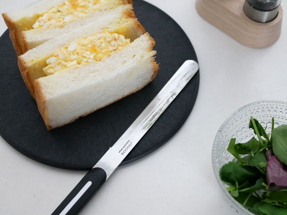 朝食のテーブルに配置されたアルコスのパールホワイトテーブルナイフ、パン、チーズ、食器類が並ぶシーン