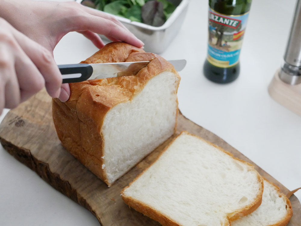 パールホワイトのアルコステーブルナイフとスライスされた白パンがカッティングボード上に配置された食卓の様子