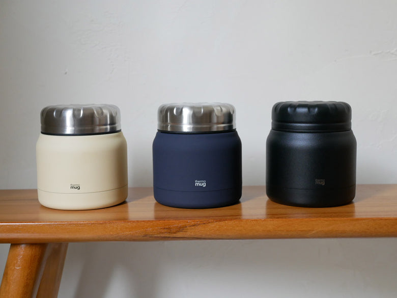 18-8ステンレス製のサーモマグミニタンクとフードコンテナが木製テーブルの上に並び、蓋付きのボックスとともに整然と配置されている様子