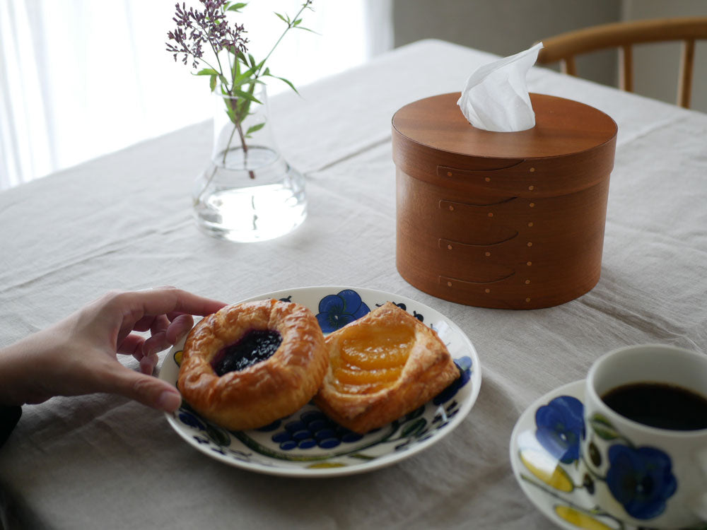 チェリー材の【アクシス】シェーカーティッシュボックスがテーブルウェアやデザートと共にダイニングテーブル上に配置されている