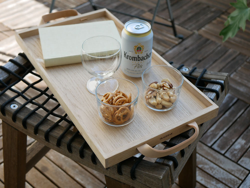 フリッツ・ハンセンのオークとレザー製Skagerak Norr Tray上にテーブルウェアや飲食物が配置されたテーブル