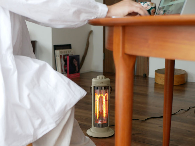 木製フローリング上に置かれたブルーノのノスタルジックなミニカーボンヒーターと円柱型ランプ