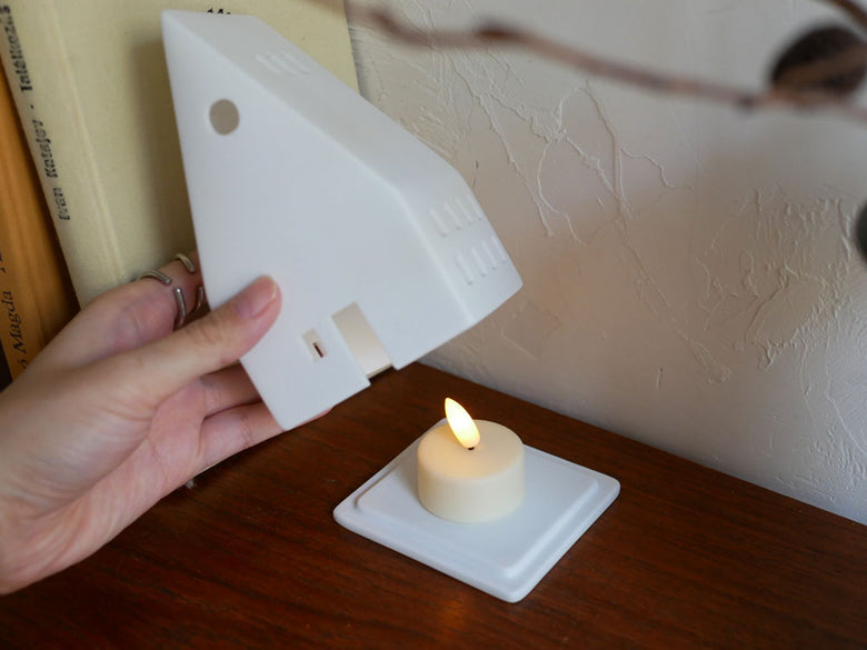 レダーLight House キャンドルホルダーとデザイン性の高いナイトライトが木製テーブルに並べられた落ち着いたインテリア写真